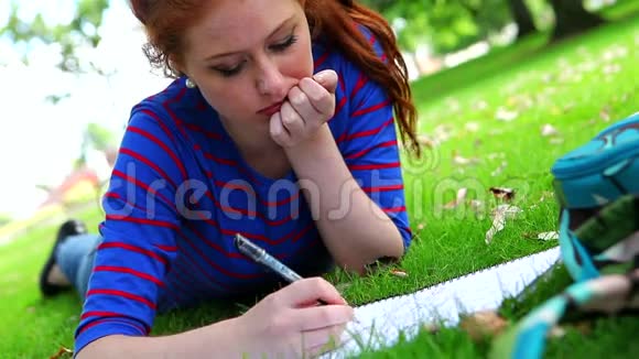 年轻漂亮的学生躺在草地上学习视频的预览图