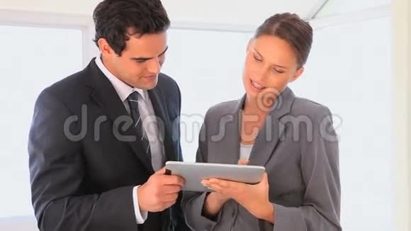 商人们看着平板电脑视频的预览图