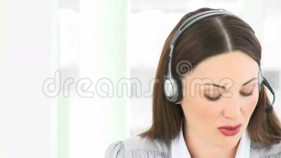 有魅力的女人在办公室里用耳机说话视频的预览图
