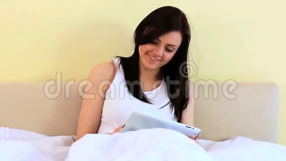 微笑的女人用数码平板电脑视频的预览图