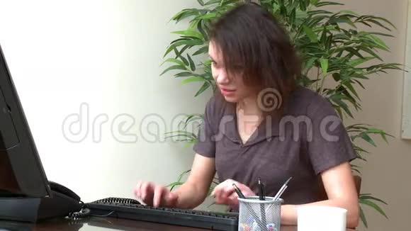 一个穿着衣服的女人在电脑上工作视频的预览图