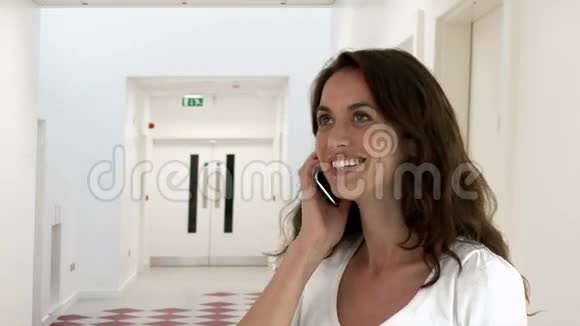 微笑的年轻女人在电话里说话视频的预览图
