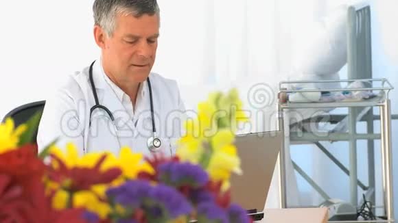 成熟的医生在他的笔记本电脑上工作视频的预览图