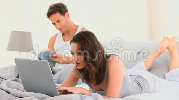 女人躺在床上用笔记本电脑工作视频的预览图