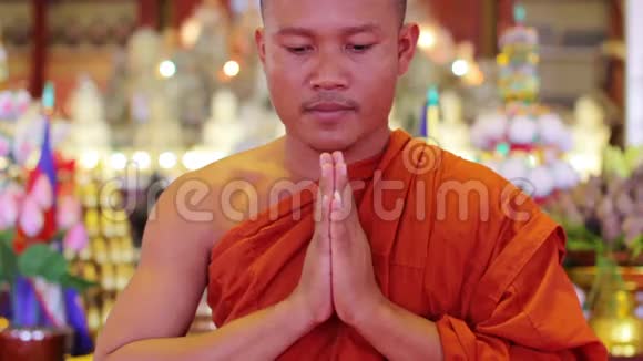 僧人身穿橘色长袍在寺庙内祈祷视频的预览图