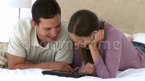 一对夫妇用电脑平板电脑躺在床上视频的预览图