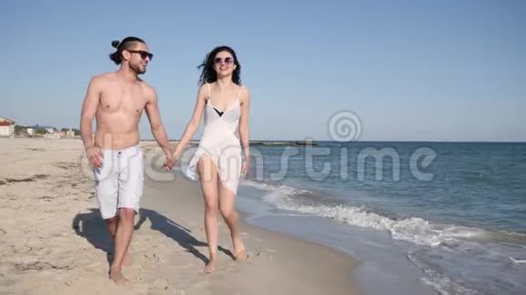 情侣们在沙滩上浪漫地散步情侣们赤着脚在沙滩上散步夏天情侣们异国情调视频的预览图