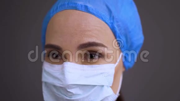 戴防护面罩的严肃外科医生或护士向前看侧面戴手术帽的女性保健专业人员视频的预览图