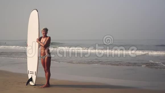 苗条迷人的成熟女人沙滩上有冲浪板视频的预览图