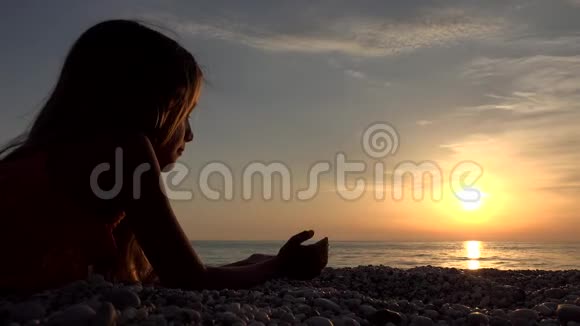 海滩上的孩子日落时在岸上玩耍的孩子日落时看海景的青少年女孩视频的预览图