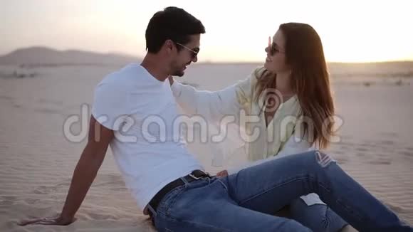 年轻人和女人在沙漠中的沙滩上玩得很开心美丽的情侣疯狂相爱背景是沙丘景观轻微的黄昏视频的预览图