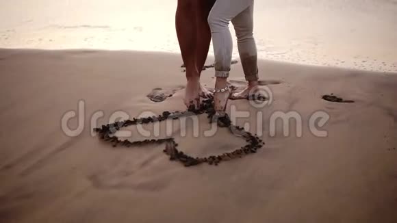 情侣男女用脚在湿沙心上作画海边的白人情侣视频的预览图