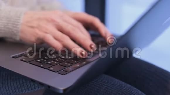 晚上当蓝色的时刻已经来到窗外时特写的女性双手在笔记本电脑键盘上打字视频的预览图