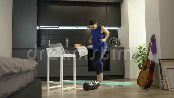 强壮的运动女性在厨房里积极慢跑和做健身在线运动在家接受女性培训视频的预览图