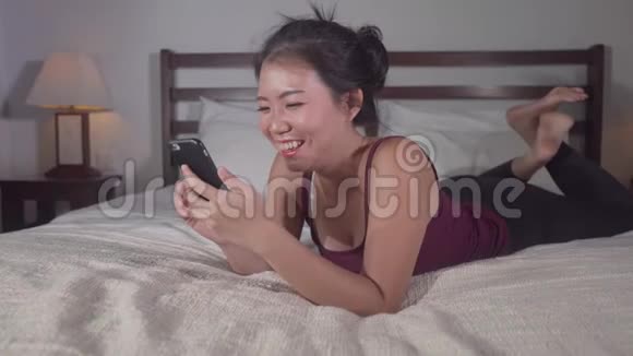 年轻美丽快乐的亚裔韩国女性使用手机社交媒体与男友发短信或享受网上约会视频的预览图