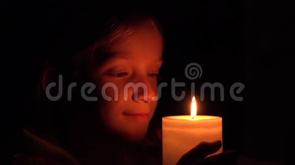 蜡烛旁悲伤的孩子夜晚祈祷的孩子忧郁的女孩肖像脸视频的预览图