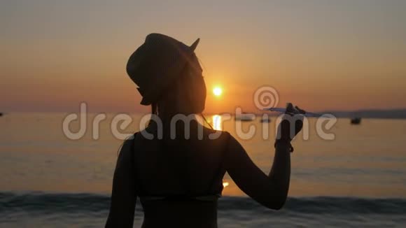 剪影女孩在日落时在热带海滩玩玩具飞机手拿小飞机特写放松时间视频的预览图
