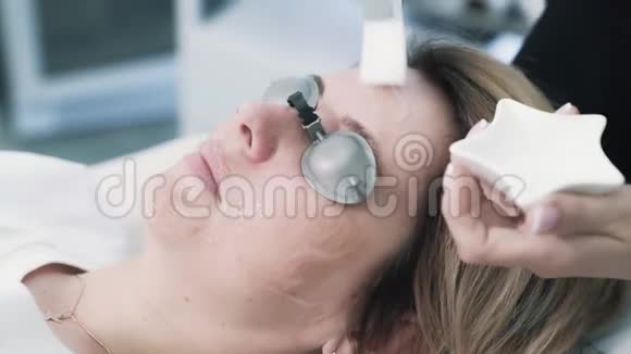 密切美容医生的双手将保护油血清涂在病人面部视频的预览图