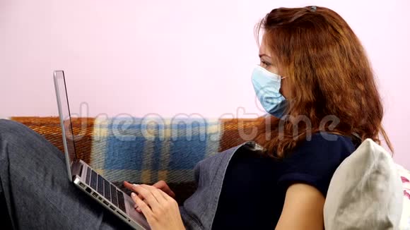 一名年轻妇女在检疫期间戴着医用口罩在家里工作社会距离视频的预览图