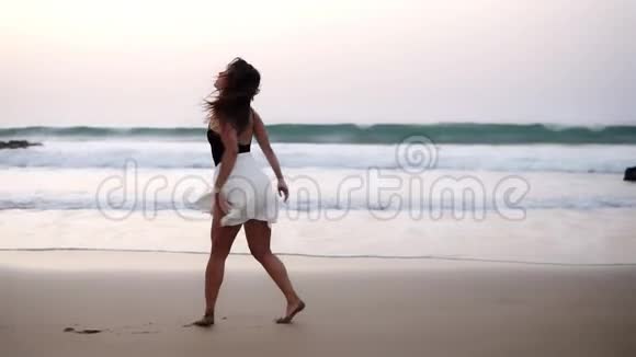 性感的女孩穿着黑色泳衣白色衬衫腹部紧绷走在海边的沙滩上华丽的长衫视频的预览图