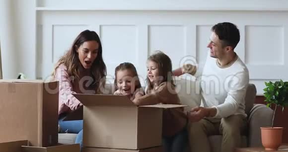 微笑的小孩子帮助幸福的年轻夫妇父母打开物品视频的预览图
