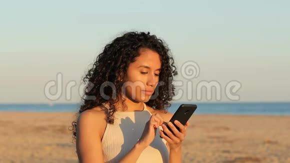 兴奋的拉丁女人在海滩上看电话视频的预览图
