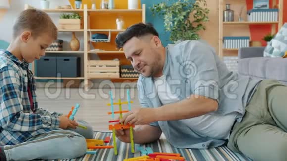 成年男子和小男孩在家玩木玩具说笑视频的预览图