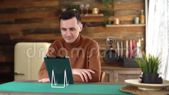 英俊的高加索年轻人使用平板电脑进行在线视频聊天视频的预览图