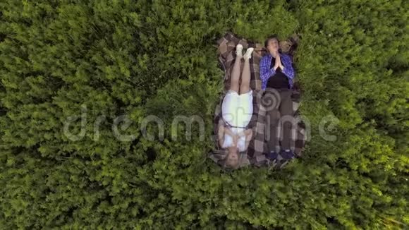 那个家伙和那个女孩躺在绿茵场上双手交叉在他面前空中观景视频的预览图