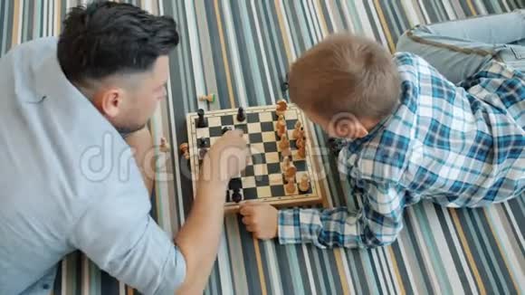 从高角度看男人和聪明的孩子在家下棋然后做击掌视频的预览图