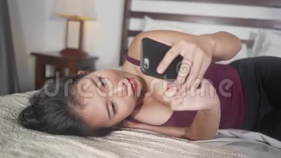 年轻美丽快乐的韩国女性使用手机社交媒体与男友发短信或享受网上约会视频的预览图
