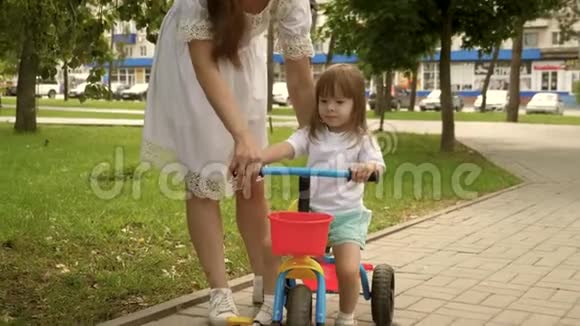 父母和小女儿在公园散步快乐妈妈教小女儿骑自行车妈妈玩她的孩子视频的预览图