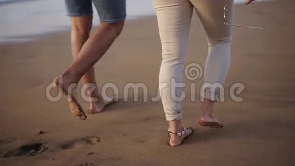 结婚的年轻夫妇在海滩上漫步在浪漫的日出时牵手男女旅行放松视频的预览图