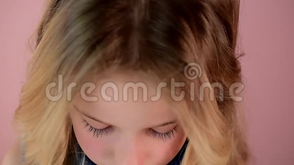 有着金色头发和蓝眼睛的长长睫毛的可爱小女孩视频的预览图