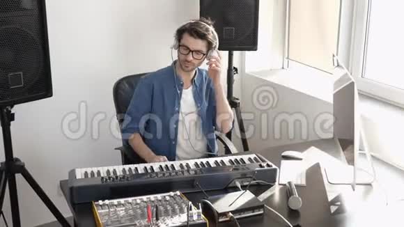 录音室的年轻人坐在前面的键盘和调整声音混合控制台听音乐视频的预览图