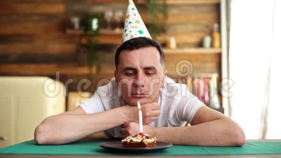 孤独的人坐在小蛋糕前面点燃蜡烛吹着它视频的预览图
