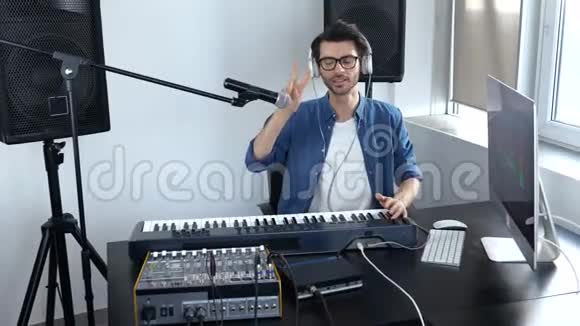 录音室的年轻人男性视频博客拍摄热与混合控制台和键盘工作音乐家视频的预览图
