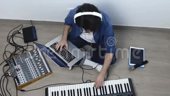 录音室的年轻人他坐在地板上用笔记本电脑和声音混合控制台工作录音音乐视频的预览图