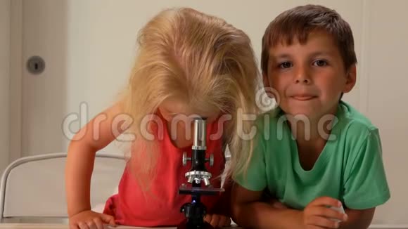 男孩正在看摄像机而一个可爱的女孩正在看显微镜视频的预览图