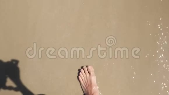 人的脚沿着海水边走在沙滩上投下阴影视频的预览图