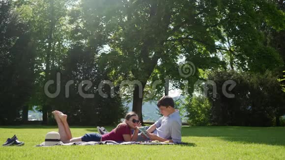 恋爱中的情侣野餐时在草坪上放松他读了一本有趣的书视频的预览图