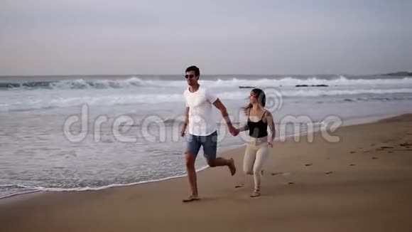 欧洲夫妇正在海滩上跑步女孩跳进男朋友的怀里他在美丽的海边把她旋转视频的预览图