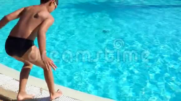 戴着泳镜的男孩正在跳着筋斗跳进游泳池视频的预览图