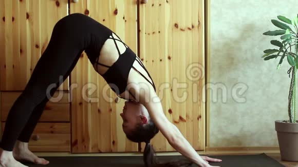 一个漂亮的年轻女孩在家练习瑜伽一个年轻漂亮的女孩表演体式改善了她的身体视频的预览图
