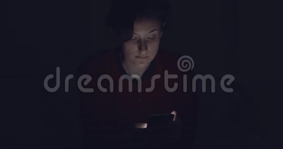 在黑暗中和朋友用手机聊天的女人视频的预览图