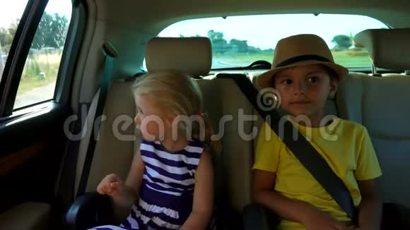 小男孩和小女孩正坐在后座上指着车窗视频的预览图
