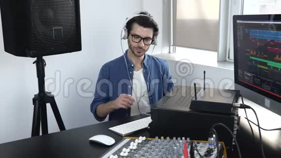 录音室的年轻人他使用专业的混合控制台喜欢听音乐视频的预览图