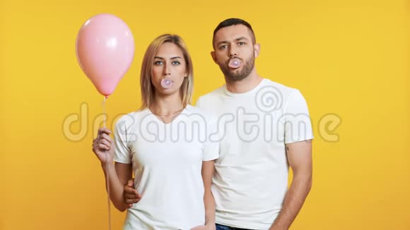 年轻夫妇用口香糖吹泡泡拿着粉红色的气球视频的预览图
