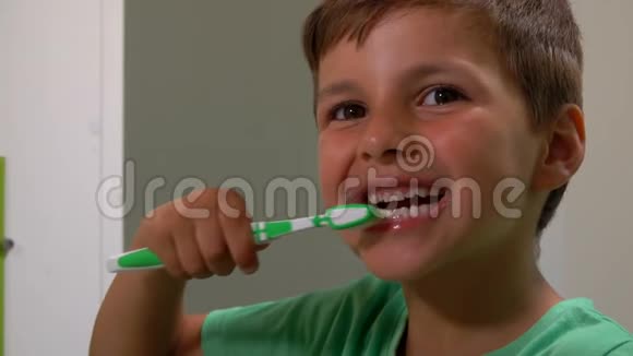 穿绿色t恤的小男孩正在浴室里刷牙视频的预览图