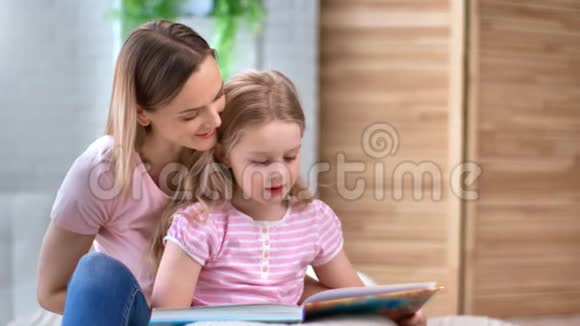 关爱的母亲在卧室里专心听可爱的女儿看书4k龙红相机视频的预览图